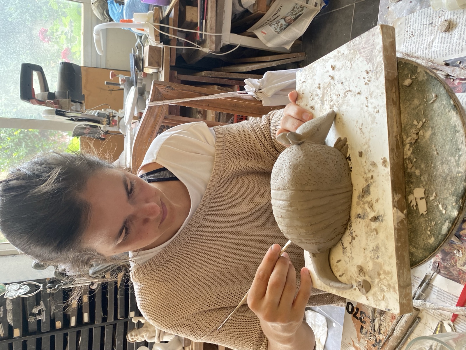 Alumna dando textura a una escultura de arcilla